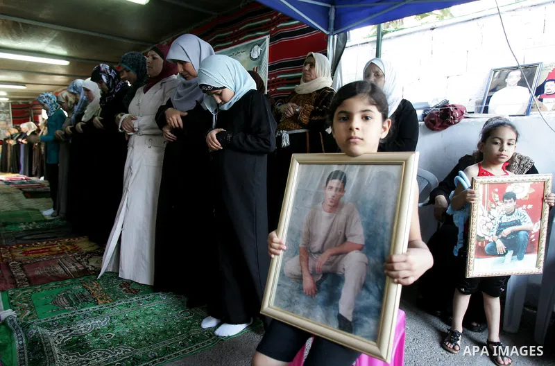 Palestinians hold photographs of their relatives held in Israeli jails during a protest calling for their release, next to the headquarters of the International Red Cross in Jerusalem, October 14, 2011. Israeli soldier G...