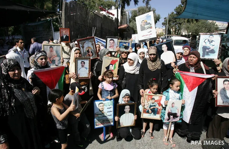 Palestinians hold photographs of their relatives held in Israeli jails during a protest calling for their release, next to the headquarters of the International Red Cross in Jerusalem, October 14, 2011. Israeli soldier G...