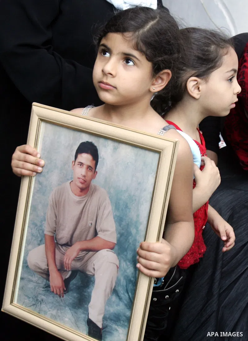 Palestinians hold photographs of their relatives held in Israeli jails during a protest calling for their release, next to the headquarters of the International Red Cross in Jerusalem, October 14, 2011. Israeli soldier G...