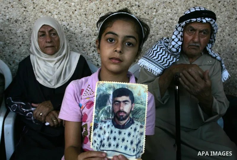 The family of Palestinian prisoner Nasser Nazzal show his picture as they gather at a relative's house in the southern Gaza Strip town of Khan Younis on October 15, 2011 awaiting his release as part of a deal to secure t...