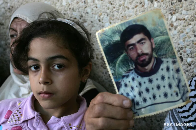 The family of Palestinian prisoner Nasser Nazzal show his picture as they gather at a relative's house in the southern Gaza Strip town of Khan Younis on October 15, 2011 awaiting his release as part of a deal to secure t...