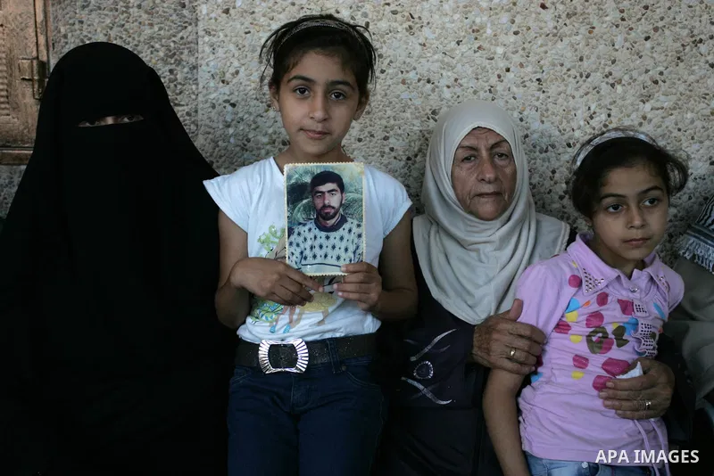 The family of Palestinian prisoner Nasser Nazzal show his picture as they gather at a relative's house in the southern Gaza Strip town of Khan Younis on October 15, 2011 awaiting his release as part of a deal to secure t...