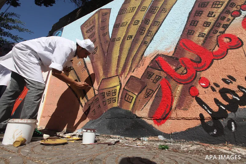 Palestinian artist paints a mural to talk about the challenge of young Palestinians with a high population of the world's 7 billion people in Gaza City, on Oct 16, 2011. Photo by Majdi Fathi