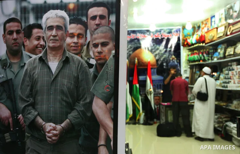 A Palestinian vendor displays pictures of Palestinian prisoners held in Israeli jails at his shop in Gaza City, Sunday, Oct. 16, 2011. The relatives of Israelis killed in Palestinian attacks waged a charged debate Sunday...