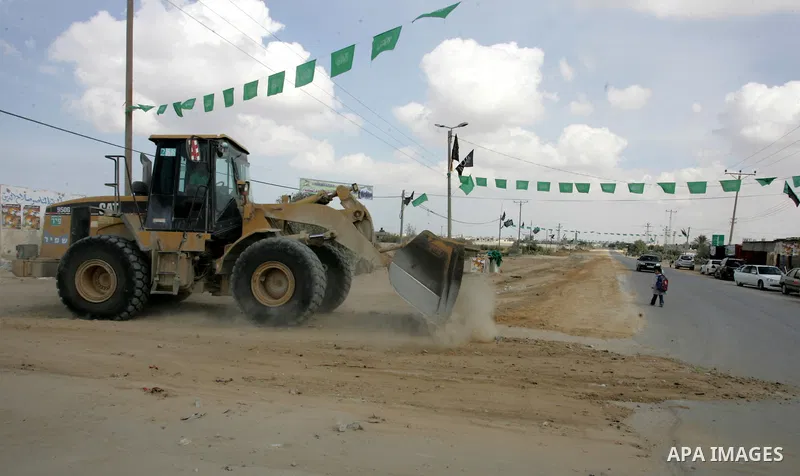 A Palestinian Hamas supporter hangs green Islamic flags as decoration ahead of the upcoming prisoner swap, at the entrance to the Rafah border crossing, southern Gaza Strip, Monday, Oct. 17, 2011. The exchange between Is...