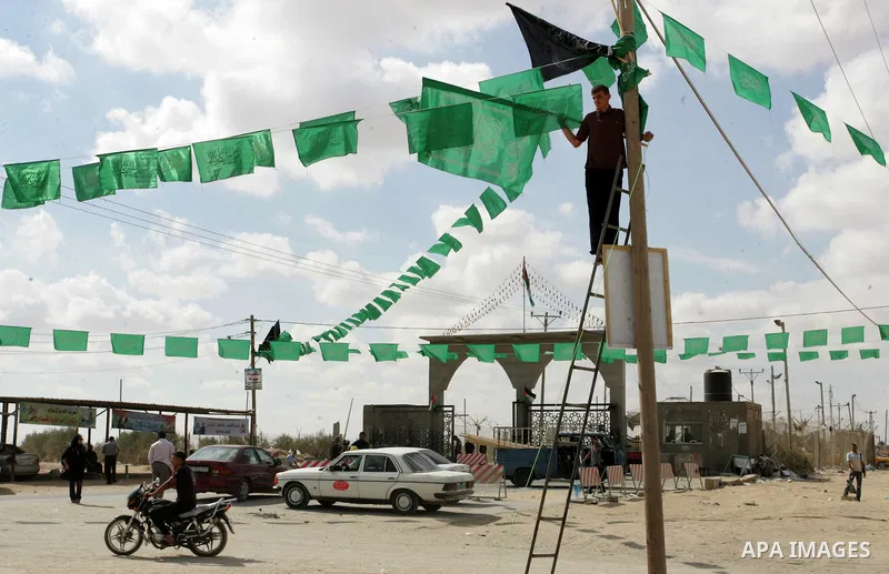 A Palestinian Hamas supporter hangs green Islamic flags as decoration ahead of the upcoming prisoner swap, at the entrance to the Rafah border crossing, southern Gaza Strip, Monday, Oct. 17, 2011. The exchange between Is...