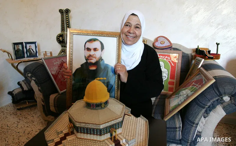The mother of Palestinian prisoner Adnan Maragha from the east Jerusalem neighbourhood of Silwan, on October 17, 2011, holds a picture of her son, who is among the 1,027 Palestinian prisoners to be freed in exchange for...