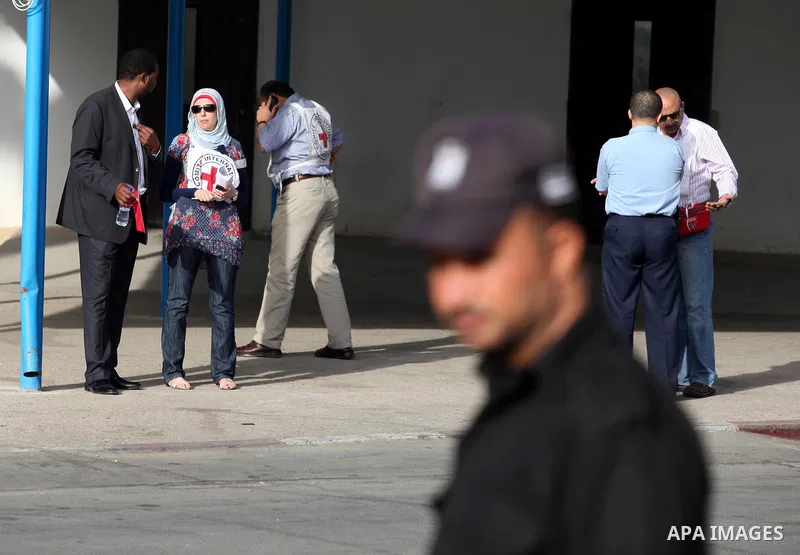 Members of the International Red Cross wait at the Rafah crossing with Egypt in the southern Gaza Strip on October 18, 2011 as an Israeli-Palestinian prisoner swap deal gets under way. Buses carrying 477 Palestinian pris...