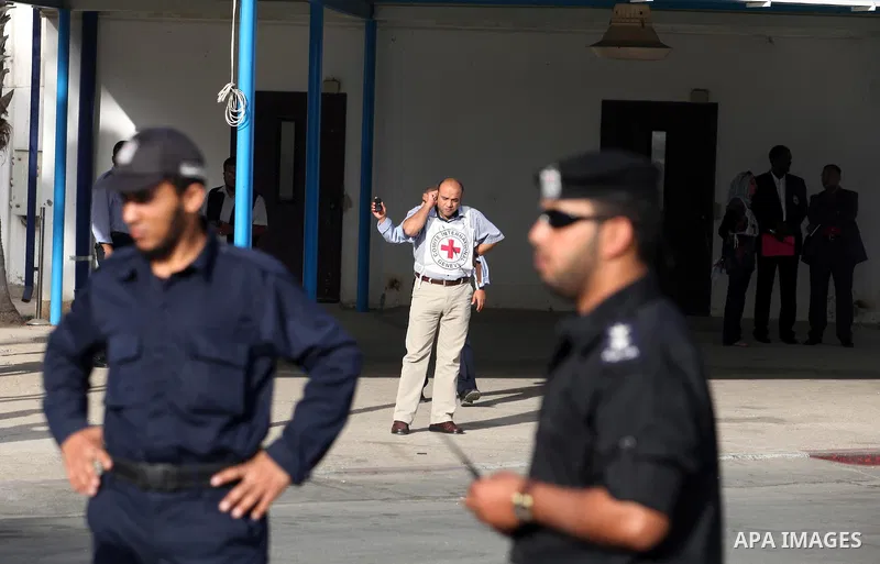 Members of the International Red Cross wait at the Rafah crossing with Egypt in the southern Gaza Strip on October 18, 2011 as an Israeli-Palestinian prisoner swap deal gets under way. Buses carrying 477 Palestinian pris...