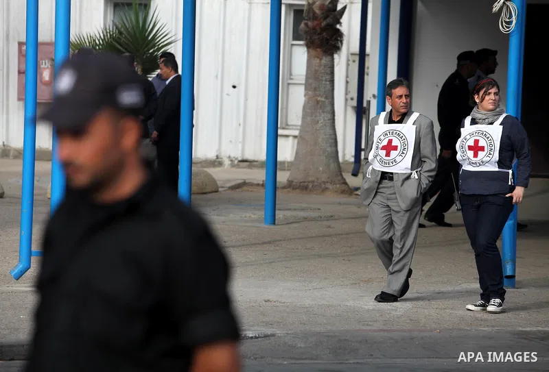 Members of the International Red Cross wait at the Rafah crossing with Egypt in the southern Gaza Strip on October 18, 2011 as an Israeli-Palestinian prisoner swap deal gets under way. Buses carrying 477 Palestinian pris...