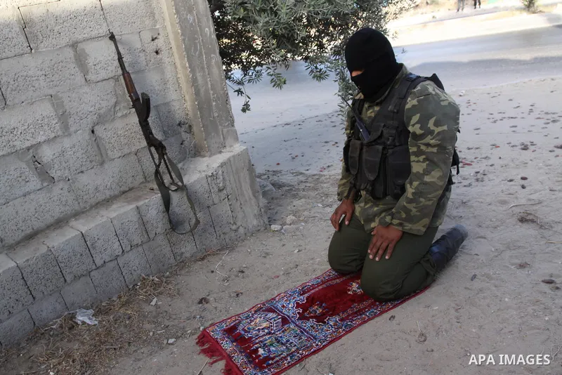 An armed Palestinian Hamas militant prays as he stands guard at a street in Gaza city on October 18, 2011 as an Israeli-Palestinian prisoner swap deal gets under way. Buses carrying 477 Palestinian prisoners were headed...