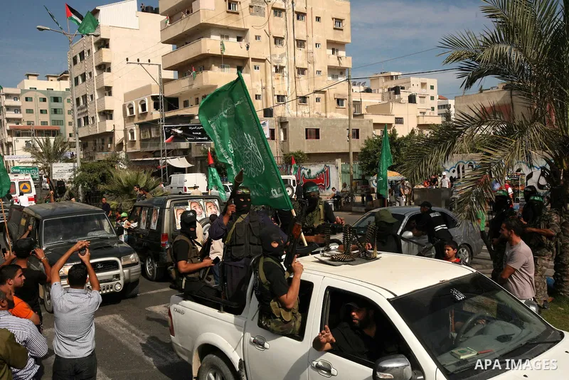 Palestinians keep watch as Hamas militants stand guard in Gaza City on October 18, 2011 as an Israeli-Palestinian prisoner swap deal gets under way. Captive Israeli soldier Gilad Shalit was today freed from five years of...