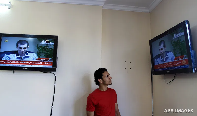 A Palestinian man watches Egypt TV Tuesday Oct 18 2011 as Israeli soldier Gilad Schalit is seen at an undisclosed location, during a pre-recorded interview released Tuesday. Schalit was moved in to Egypt from captivity i...