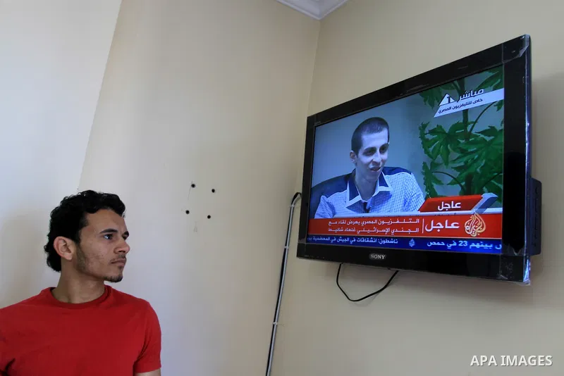 A Palestinian man watches Egypt TV Tuesday Oct 18 2011 as Israeli soldier Gilad Schalit is seen at an undisclosed location, during a pre-recorded interview released Tuesday. Schalit was moved in to Egypt from captivity i...