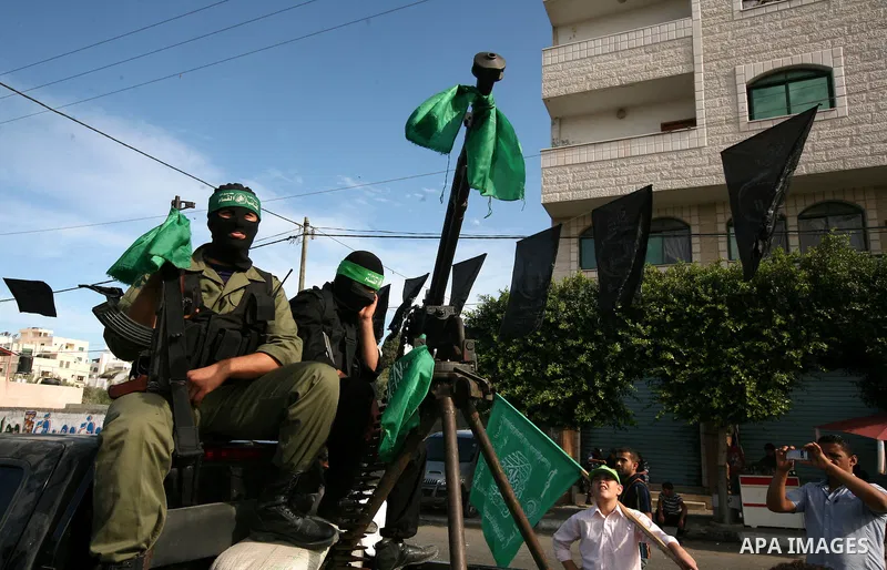 Palestinians keep watch as Hamas militants stand guard in Gaza City on October 18, 2011 as an Israeli-Palestinian prisoner swap deal gets under way. Captive Israeli soldier Gilad Shalit was today freed from five years of...