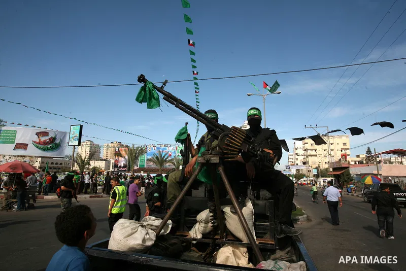 Palestinians keep watch as Hamas militants stand guard in Gaza City on October 18, 2011 as an Israeli-Palestinian prisoner swap deal gets under way. Captive Israeli soldier Gilad Shalit was today freed from five years of...