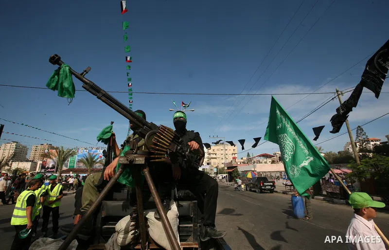 Palestinians keep watch as Hamas militants stand guard in Gaza City on October 18, 2011 as an Israeli-Palestinian prisoner swap deal gets under way. Captive Israeli soldier Gilad Shalit was today freed from five years of...