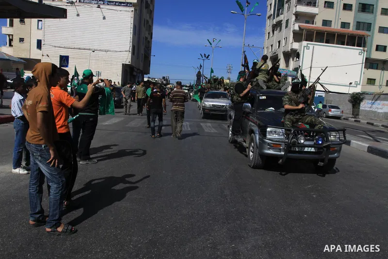 Palestinians keep watch as Hamas militants stand guard in Gaza City on October 18, 2011 as an Israeli-Palestinian prisoner swap deal gets under way. Captive Israeli soldier Gilad Shalit was today freed from five years of...