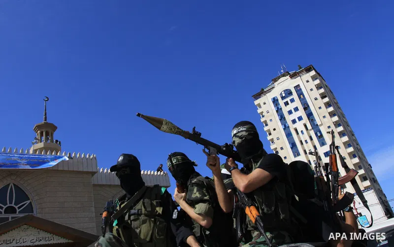 Palestinians keep watch as Hamas militants stand guard in Gaza City on October 18, 2011 as an Israeli-Palestinian prisoner swap deal gets under way. Captive Israeli soldier Gilad Shalit was today freed from five years of...