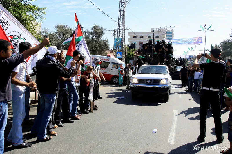 Palestinians keep watch as Hamas militants stand guard in Gaza City on October 18, 2011 as an Israeli-Palestinian prisoner swap deal gets under way. Captive Israeli soldier Gilad Shalit was today freed from five years of...