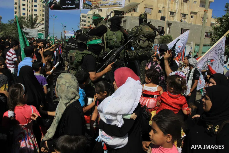 Palestinians keep watch as Hamas militants stand guard in Gaza City on October 18, 2011 as an Israeli-Palestinian prisoner swap deal gets under way. Captive Israeli soldier Gilad Shalit was today freed from five years of...