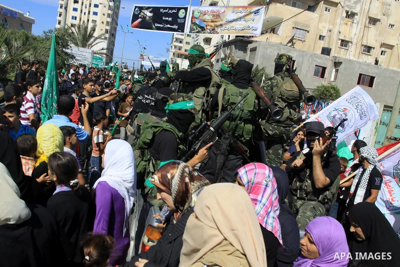 Palestinians keep watch as Hamas militants stand guard in Gaza City on October 18, 2011 as an Israeli-Palestinian prisoner swap deal gets under way. Captive Israeli soldier Gilad Shalit was today freed from five years of...