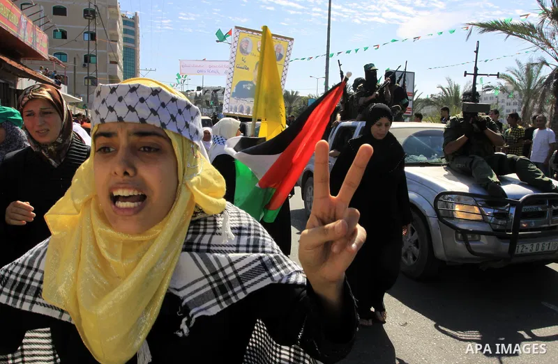 Palestinians keep watch as Hamas militants stand guard in Gaza City on October 18, 2011 as an Israeli-Palestinian prisoner swap deal gets under way. Captive Israeli soldier Gilad Shalit was today freed from five years of...