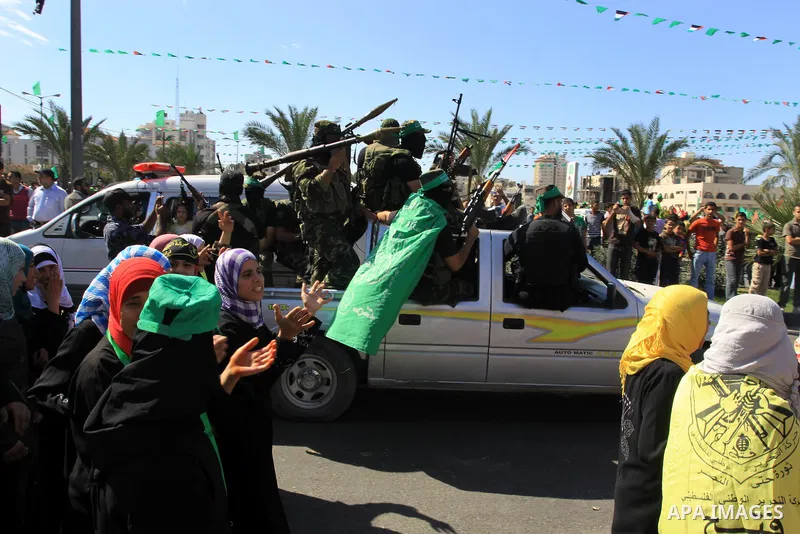 Palestinians keep watch as Hamas militants stand guard in Gaza City on October 18, 2011 as an Israeli-Palestinian prisoner swap deal gets under way. Captive Israeli soldier Gilad Shalit was today freed from five years of...