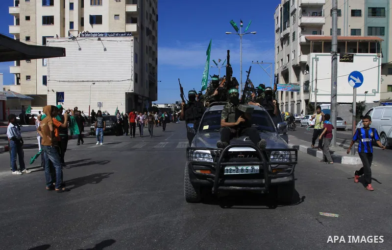 Palestinians keep watch as Hamas militants stand guard in Gaza City on October 18, 2011 as an Israeli-Palestinian prisoner swap deal gets under way. Captive Israeli soldier Gilad Shalit was today freed from five years of...