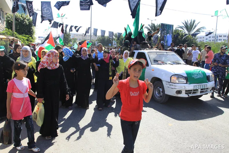 Palestinians keep watch as Hamas militants stand guard in Gaza City on October 18, 2011 as an Israeli-Palestinian prisoner swap deal gets under way. Captive Israeli soldier Gilad Shalit was today freed from five years of...