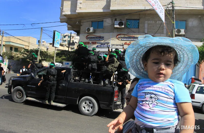 Palestinians keep watch as Hamas militants stand guard in Gaza City on October 18, 2011 as an Israeli-Palestinian prisoner swap deal gets under way. Captive Israeli soldier Gilad Shalit was today freed from five years of...