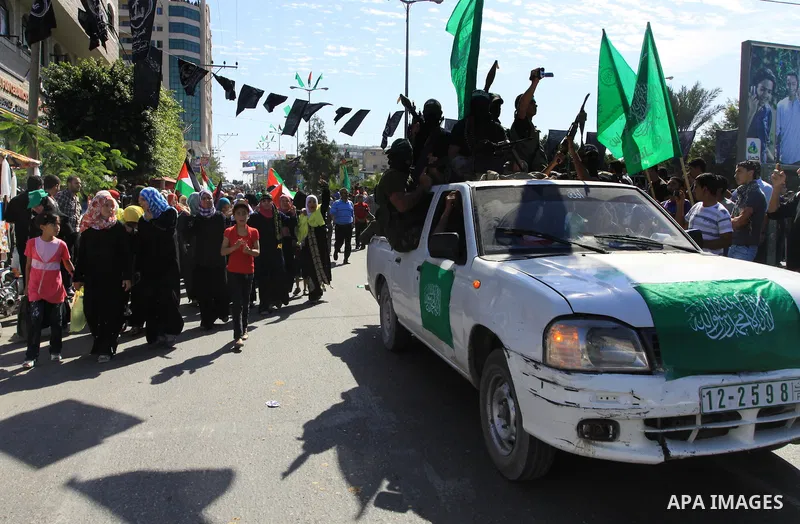 Palestinians keep watch as Hamas militants stand guard in Gaza City on October 18, 2011 as an Israeli-Palestinian prisoner swap deal gets under way. Captive Israeli soldier Gilad Shalit was today freed from five years of...