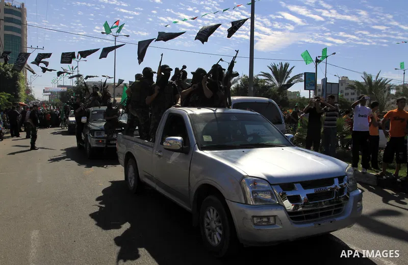Palestinians keep watch as Hamas militants stand guard in Gaza City on October 18, 2011 as an Israeli-Palestinian prisoner swap deal gets under way. Captive Israeli soldier Gilad Shalit was today freed from five years of...