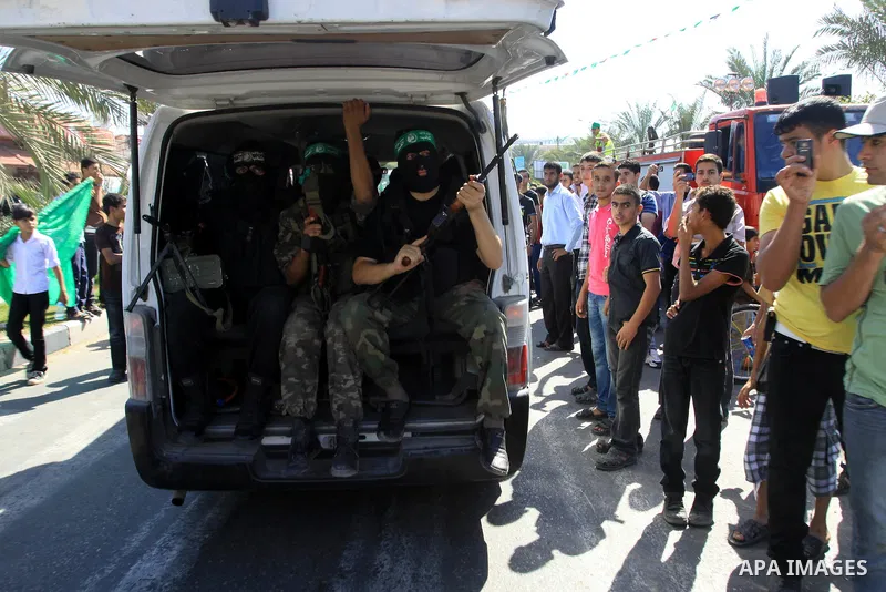 Palestinians keep watch as Hamas militants stand guard in Gaza City on October 18, 2011 as an Israeli-Palestinian prisoner swap deal gets under way. Captive Israeli soldier Gilad Shalit was today freed from five years of...