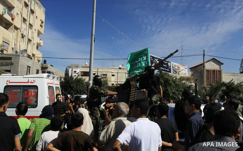 Palestinians keep watch as Hamas militants stand guard in Gaza City on October 18, 2011 as an Israeli-Palestinian prisoner swap deal gets under way. Captive Israeli soldier Gilad Shalit was today freed from five years of...
