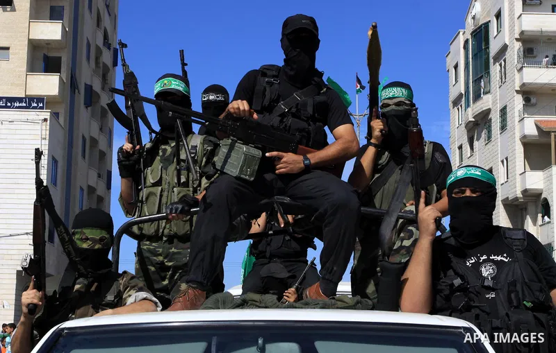 Palestinians keep watch as Hamas militants stand guard in Gaza City on October 18, 2011 as an Israeli-Palestinian prisoner swap deal gets under way. Captive Israeli soldier Gilad Shalit was today freed from five years of...