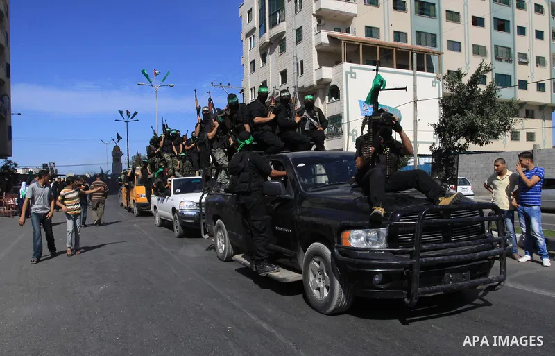 Palestinians keep watch as Hamas militants stand guard in Gaza City on October 18, 2011 as an Israeli-Palestinian prisoner swap deal gets under way. Captive Israeli soldier Gilad Shalit was today freed from five years of...