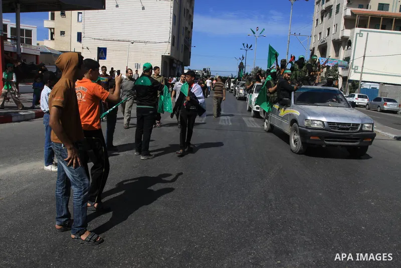 Palestinians keep watch as Hamas militants stand guard in Gaza City on October 18, 2011 as an Israeli-Palestinian prisoner swap deal gets under way. Captive Israeli soldier Gilad Shalit was today freed from five years of...
