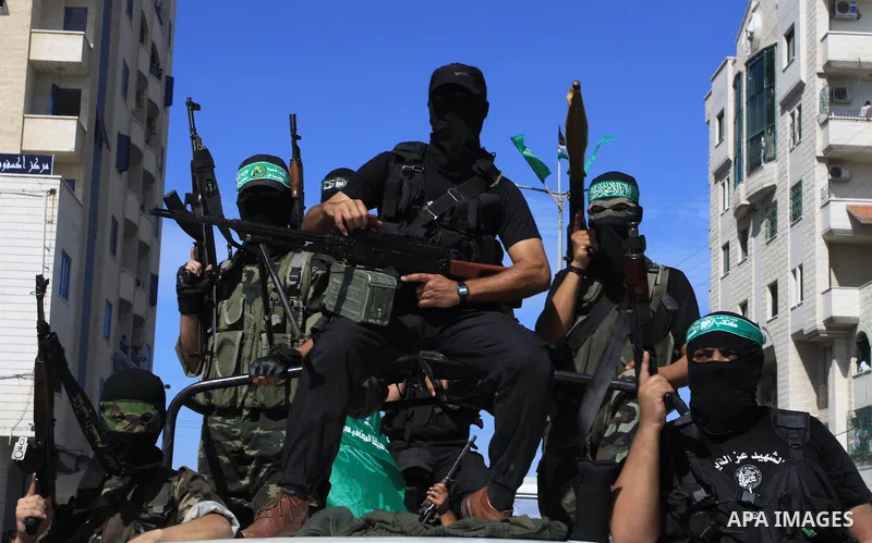 Palestinians keep watch as Hamas militants stand guard in Gaza City on October 18, 2011 as an Israeli-Palestinian prisoner swap deal gets under way. Captive Israeli soldier Gilad Shalit was today freed from five years of...