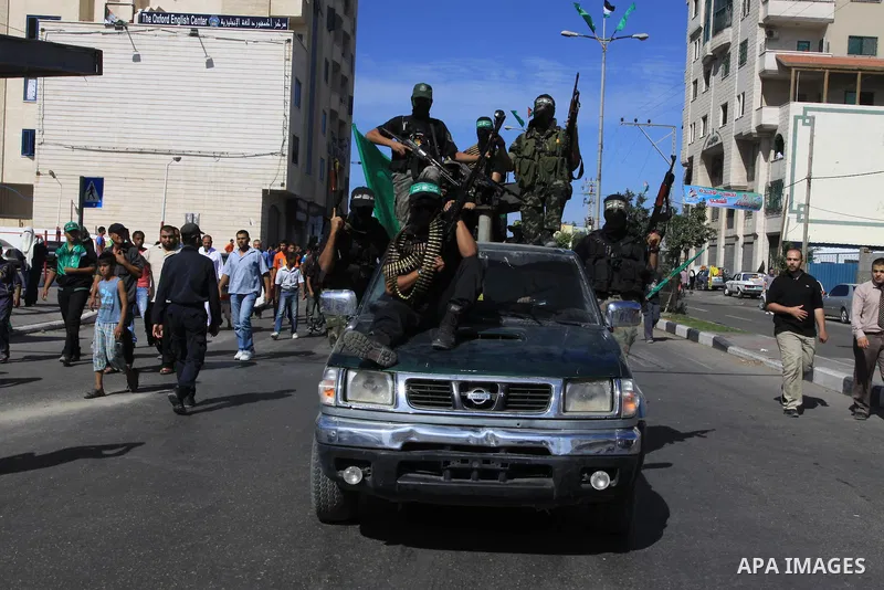 Palestinians keep watch as Hamas militants stand guard in Gaza City on October 18, 2011 as an Israeli-Palestinian prisoner swap deal gets under way. Captive Israeli soldier Gilad Shalit was today freed from five years of...