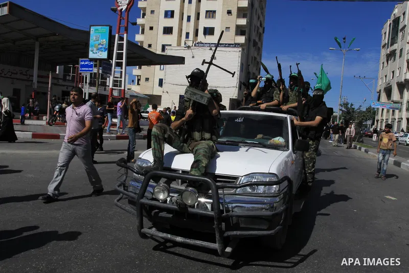 Palestinians keep watch as Hamas militants stand guard in Gaza City on October 18, 2011 as an Israeli-Palestinian prisoner swap deal gets under way. Captive Israeli soldier Gilad Shalit was today freed from five years of...