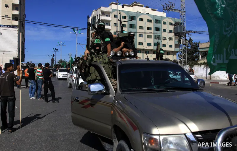 Palestinians keep watch as Hamas militants stand guard in Gaza City on October 18, 2011 as an Israeli-Palestinian prisoner swap deal gets under way. Captive Israeli soldier Gilad Shalit was today freed from five years of...