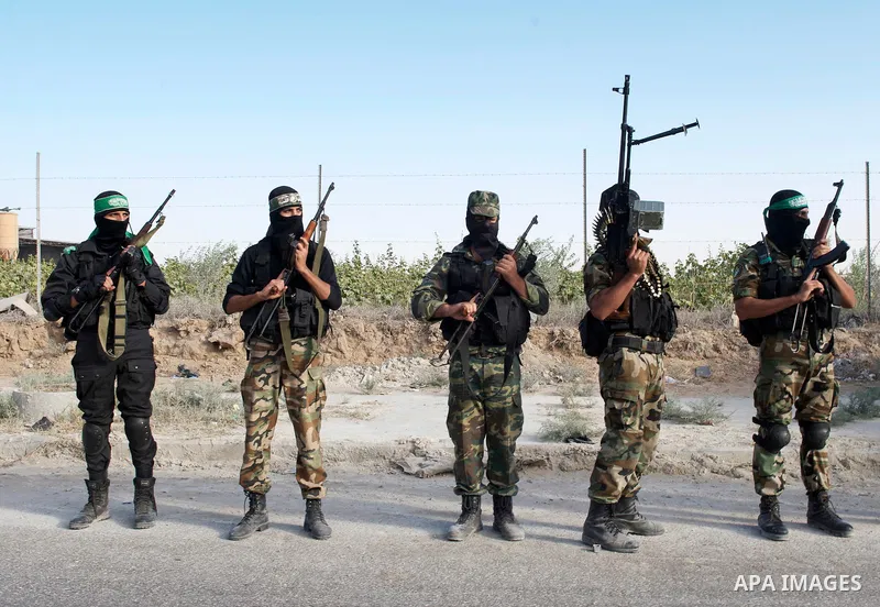 Palestinians keep watch as Hamas militants stand guard in Gaza City on October 18, 2011 as an Israeli-Palestinian prisoner swap deal gets under way. Captive Israeli soldier Gilad Shalit was today freed from five years of...