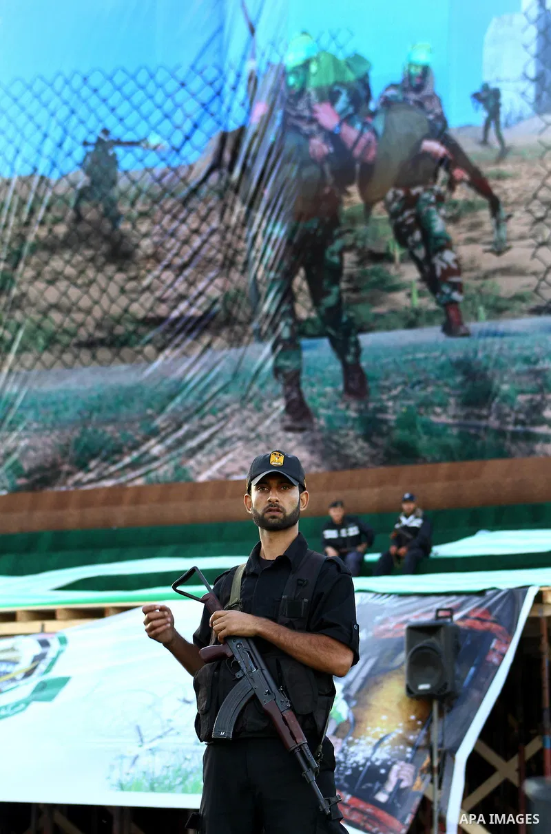 Palestinian police officers sit on stage in front of a poster showing a Hamas militant carrying an Israeli soldier on the stage erected to welcome Palestinian prisoners released in exchange for the captured Israeli soldi...