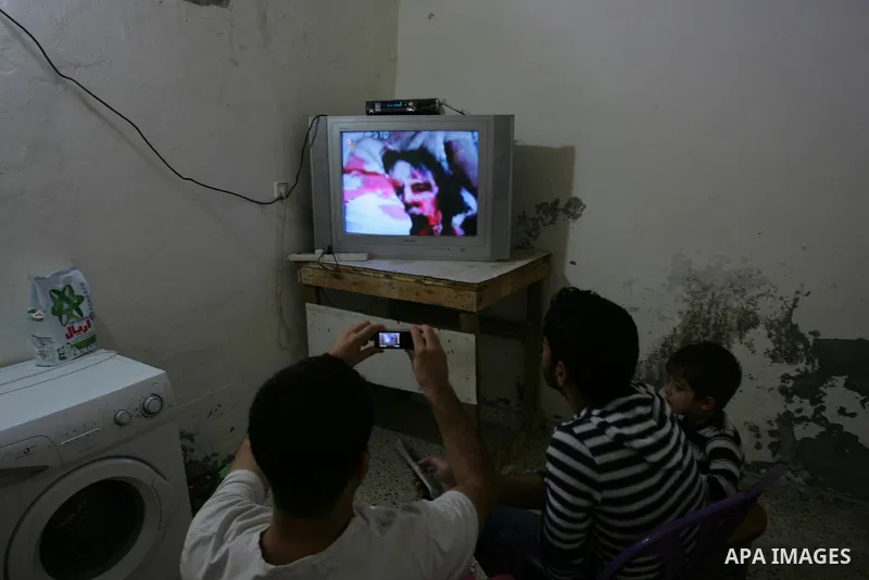 Palestinians watch television news the killing of the Libyan leader,in their home in a refugee camp in Rafah, southern Gaza Strip on October 20, 2011. Head of the military in the city of Tripoli, "Abdel Hakim Belhadj, "...