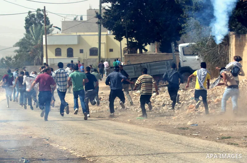 Palestinian demonstrators run for cover from tear gas canisters fired by Israeli border police officers as they demand access to their land near Kufr Qaddum, close to the northern West Bank Jewish settlement of Kdumim, F...