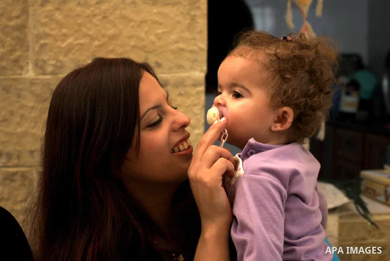 Freed Palestinian prisoner Palestinian Doaa Jayyousi plays with a child at her house in the West Bank city of Tulkarem, Sunday, Oct. 23, 2011. Jayyousi, served almost 10 years of three life sentences she was given for he...