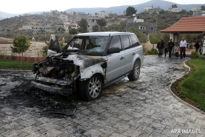 A Palestinian man inspects a burnt car in the village of Beit Furik, near the West Bank town of Nablus, on Oct. 27, 2011. Vandals set fire to a car in a West Bank village, and suspicion has fallen on Jewish settlers. Pal...