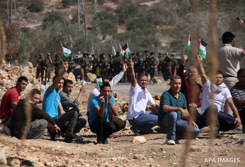 Palestinian protesters wave with their national flag in front of Israeli security forces in Kufr Qaddum near the northern West Bank Jewish settlement of Kdumim, Friday ,Friday, Oct. 28, 2011. Palestinians clashed with Is...