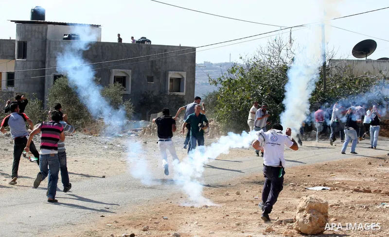 Palestinian protesters run for cover from tear gas canisters fired by Israeli security forces in Kufr Qaddum near the northern West Bank Jewish settlement of Kdumim, Friday ,Friday, Oct. 28, 2011. Palestinians clashed wi...